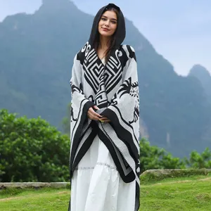 Detailaufnahme eines gestrickten Kapuzenponchos mit ethnischem Muster in Bergkulisse.