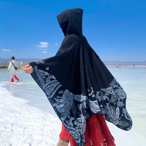 Back view of women's hooded knit poncho with ethnic paisley pattern hem for travel