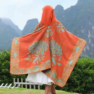 Detailansicht der Rückseite eines orangefarbenen Kapuzenponchos mit türkisfarbenem Paisley-Muster