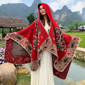 Nahaufnahme eines leuchtend roten Kapuzenponchos mit traditionellen Paisley-Jacquard-Details
