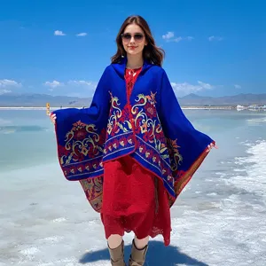 Outdoor lifestyle shot of a hooded knitted poncho with floral jacquard pattern
