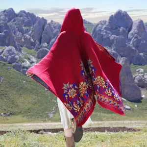 Back view of a thick red knitted hooded poncho with colorful ethnic floral patterns.