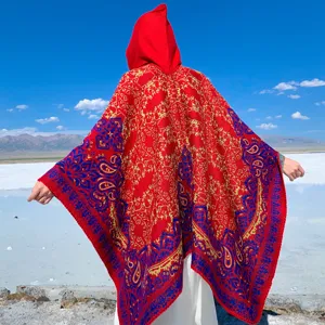 Poncho étnico rojo vibrante con capucha y patrones de paisley para viajes al aire libre.