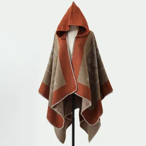 Detailansicht eines gestrickten Kapuzenponchos in Rostrot und Beige mit Mustern.