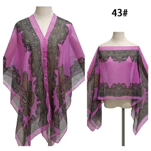 Detailansicht eines lila Paisley-Strandumhangs mit Perlenknöpfen und transparentem Stoff.