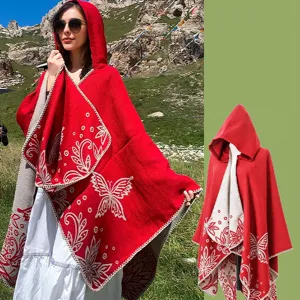 Vibrant red hooded knitted poncho featuring intricate white butterfly and floral patterns