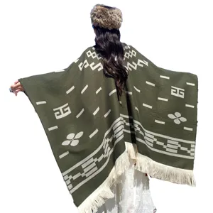 Detailansicht eines übergroßen grünen Strickponchos mit Stammesmustern und Quasten auf der Rückseite
