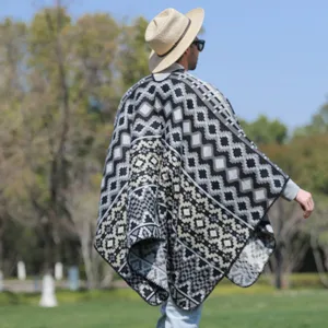 Back view of a mens warm knitted geometric pattern shawl poncho cloak outdoors.