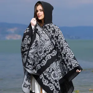 Elegante Frau in schwarz-grauem Kapuzenponcho mit Paisleymuster am Seeufer