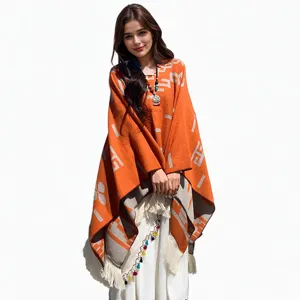 Stilvoller orangefarbener Strickponcho mit geometrischen Mustern und Quasten-Details.