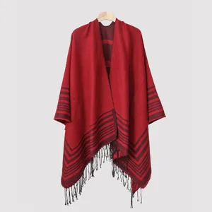 Detailed view of dark red knitted men's poncho featuring horizontal stripes and black tassels