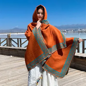 Outdoor detail of a burnt orange hooded shawl with blue Greek key pattern