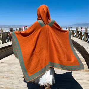Bohemian orange knit hooded poncho with turquoise Greek key pattern for travel