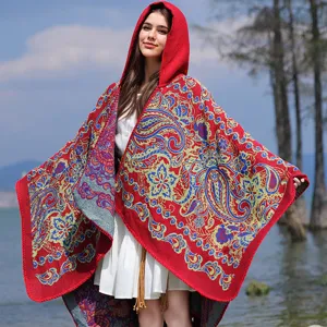 Detailansicht eines roten Strickponchos mit Kapuze und blauem Paisleymuster