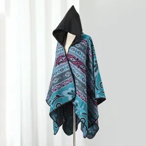 Detailansicht eines gestrickten Ponchos mit Kapuze und Paisley-Mustern in Türkis.