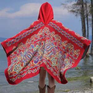 Detail eines roten gestrickten Ponchos mit Kapuze und Vintage-Paisleymuster für den Winter.