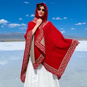 Red hooded knit shawl poncho featuring a beige Greek key pattern border for travel