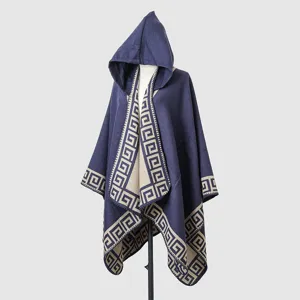 Close-up detail of blue hooded knit poncho featuring elegant Greek key pattern border