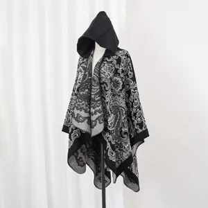 Detailansicht eines Strickponchos mit Kapuze und grau-schwarzem floralem Paisley-Muster