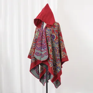 Detailansicht eines roten, gestrickten Kapuzenponchos mit aufwendigen Paisley-Blumenmustern
