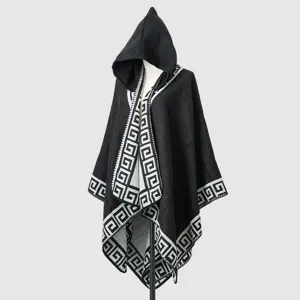 Detail view of hooded knit poncho with black geometric Greek key pattern trim on edges.
