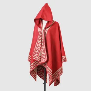 Red hooded knitted poncho with elegant Greek key border pattern and soft texture detail