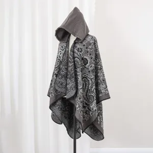 Detailansicht eines grauen Paisley-Strickponchos mit Kapuze auf einer Schaufensterpuppe