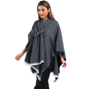 Detailed shot of a grey knit poncho with a stylish side-tie bow and frayed edges