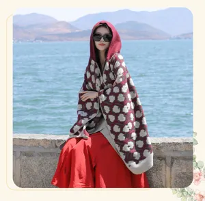 Elegant maroon hooded knit poncho shawl with floral pattern shown in scenic outdoor setting