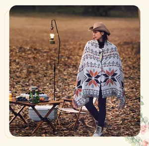 Schicke Strickschal-Decke im Ethno-Stil, getragen von einem Model beim Camping im Freien.