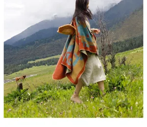 Asian woman walking in a mountain meadow wearing a thick ethnic style vintage shawl poncho