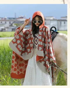 Asian woman in orange patterned hooded poncho shawl posing outdoors with a horse