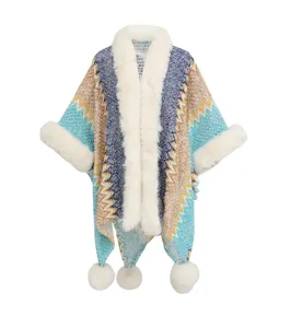Detailansicht eines ethnischen Strickponchos mit weißem Kunstpelzkragen und Pompons