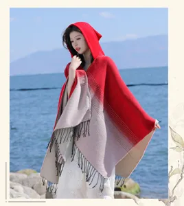 Foto van een model in een rood-beige poncho met capuchon, kleurverloop en kwasten.