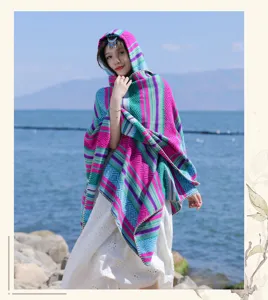 Ethnic colorful striped hooded knit shawl presented outdoors against a scenic lake background
