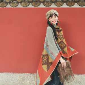Asian model wearing a colorful ethnic vintage warm shawl poncho in front of a red wall