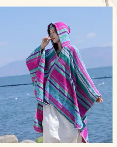 Ethnic style colorful striped hooded poncho shawl worn by an Asian model near a scenic lake