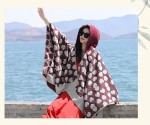 An elegant Asian woman wearing a red and grey floral hooded shawl by a scenic lake