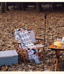 Ethnische Strickdecke mit geometrischem Muster auf einem Stuhl in Camping-Umgebung