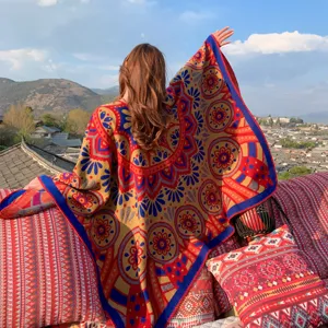 Model wearing an ethnic patterned shawl with a scenic village and mountain backdrop