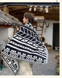 Ethno-Strickschal-Decke mit schwarz-weißen geometrischen Mustern und Fransenbesatz