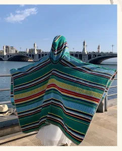 Back view of a woman wearing an ethnic striped hooded poncho by the coast.