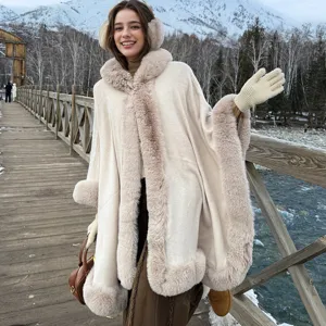 Mannequin portant un poncho en maille à bordure en fourrure beige avec montagnes.