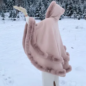 Vue détaillée d'un châle en tricot rose à capuche avec bordure en fourrure en forêt