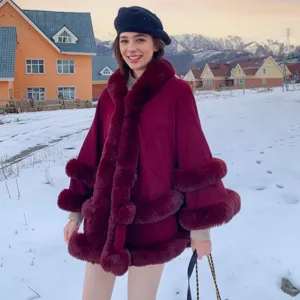 Cape en tricot bordeaux élégante avec bordure en fausse fourrure dans un décor hivernal enneigé