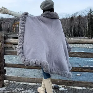 Back view of women's grey winter poncho cloak with faux fur collar in snow landscape