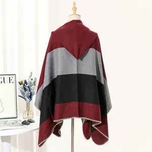 Back view of a hooded knitted poncho with bold stripes in burgundy, grey, and black.