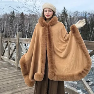Femme caucasienne portant un poncho à capuche avec bordure en fourrure dans la neige