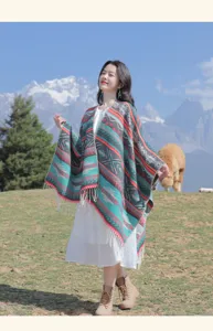 Strick-Poncho im Ethno-Stil mit bunten Mustern und Fransen vor Bergkulisse im Freien