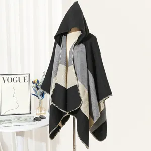 Detailed view of a hooded color-block knitted poncho in black and grey tones.
